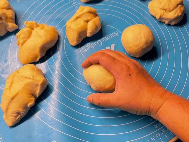 I usually tuck the dough into itself to make a smooth surface, and then roll the ball in a circular motion under a cupped hand to smooth out the seams on the bottom.